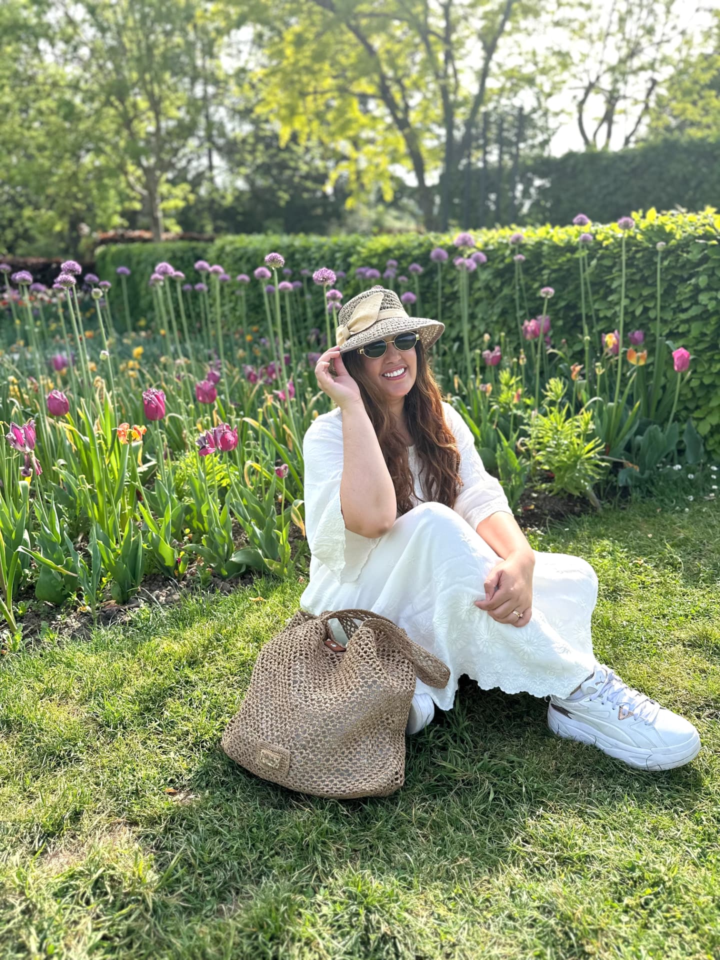 Sofi al aire libre, sentada en el pasto con un sombrero de paja y un vestido blanco